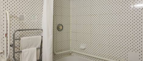 A bathroom with a shower, a grab bar, and a towel rack with two towels.