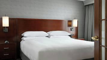 Un lit bien fait, avec des draps blancs, une tête de lit en bois et deux lampes de chevet.