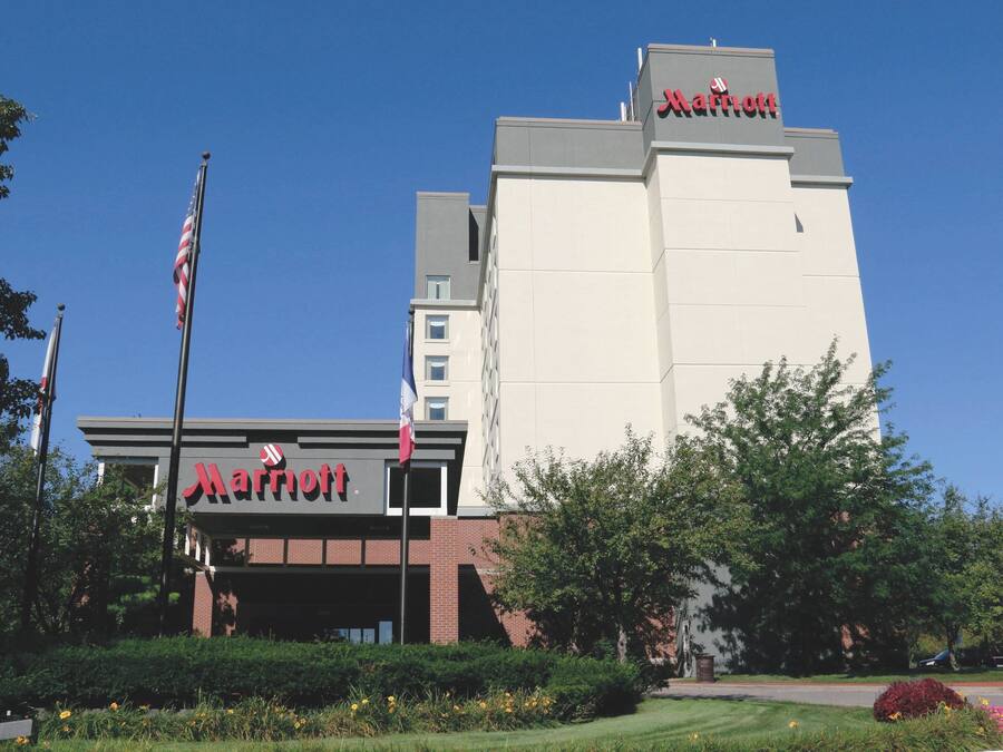 A Marriott hotel with a prominent sign, flag, and well-maintained landscaping.