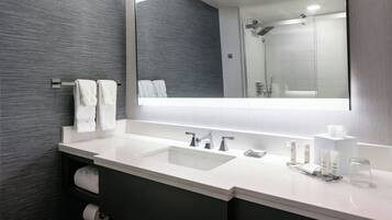 Un baño moderno con un espejo grande, dos lavamanos y una ducha.