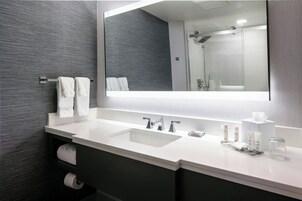 Un baño moderno con un espejo grande, dos lavamanos y una ducha.