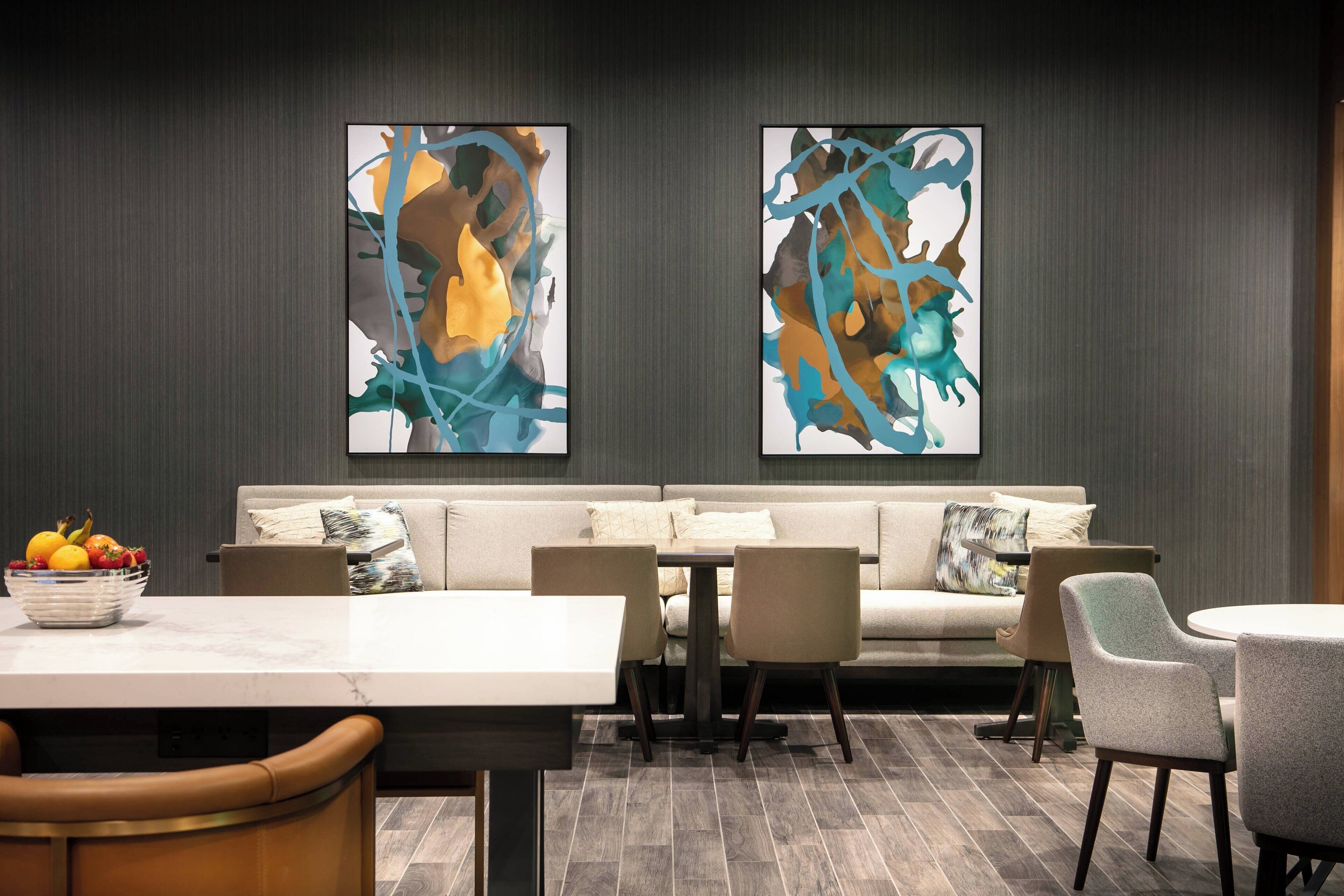 A modern dining area with a sofa, chairs, a table, and abstract art on the wall.