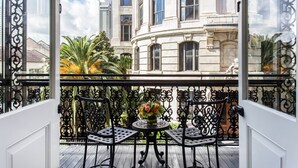 Ein Balkon mit Tisch, Stühlen, einem Blumenstrauß und Blick auf ein klassizistisches Gebäude.