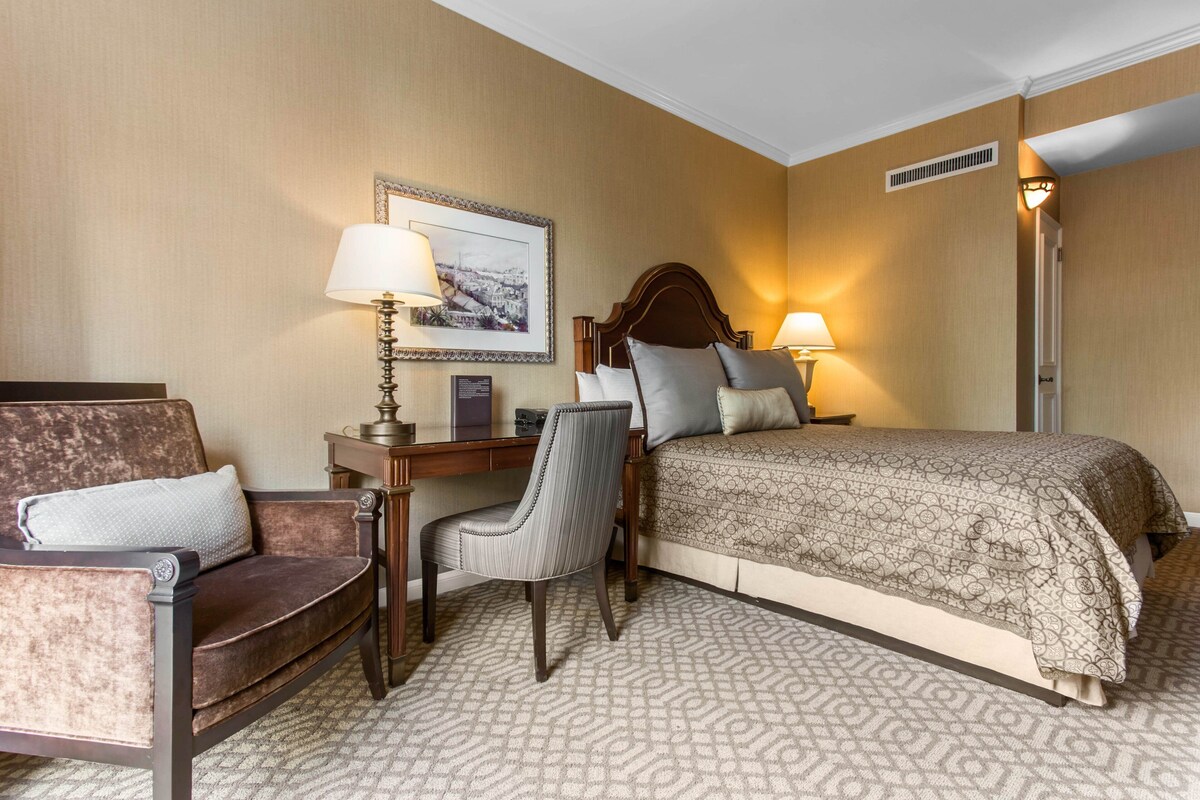 Une chambre d’hôtel avec un lit, un bureau, une chaise et une lampe.