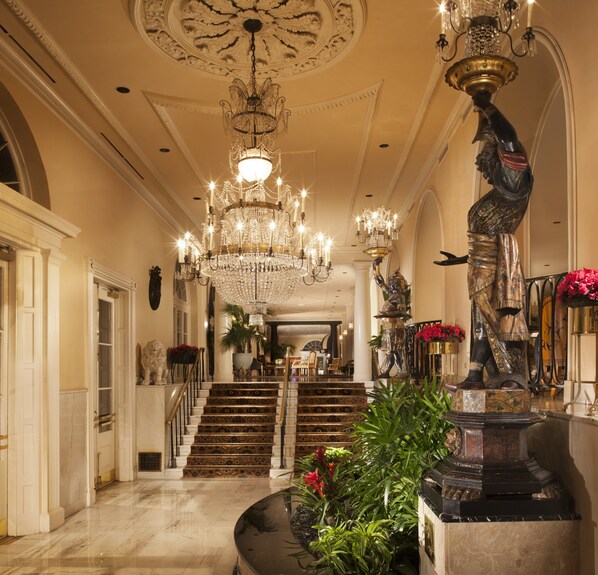 A grand hallway with a large chandelier, a statue, and a staircase. - Omni Royal Orleans Hotel (New Orleans)