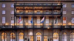 Ein mehrstöckiges Hotel mit Balkon, Bogenfenstern und Fahnen.
