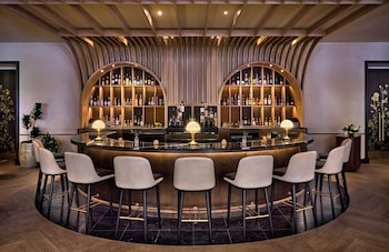 A restaurant with round tables, chandeliers, and a stone archway. at Omni Royal Orleans Hotel