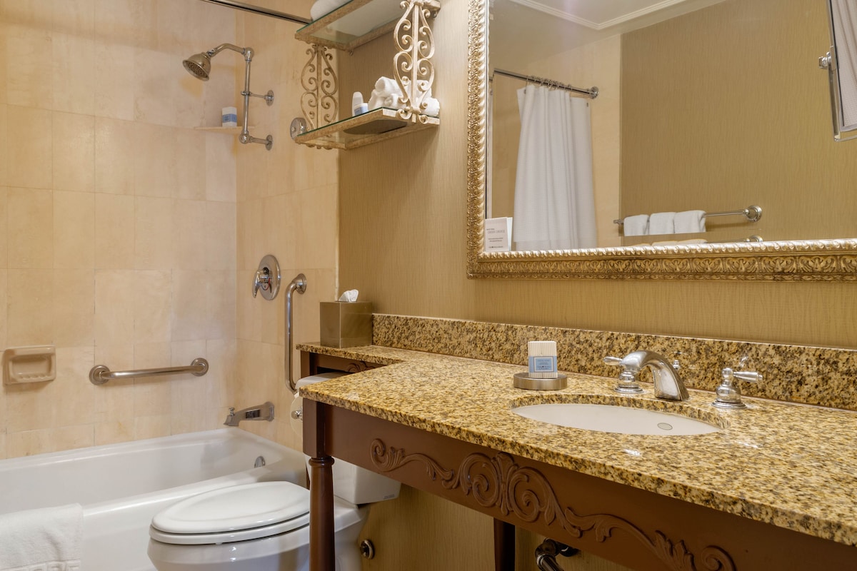 Une salle de bain équipée d’une baignoire, de toilettes, d’un lavabo et d’un grand miroir.
