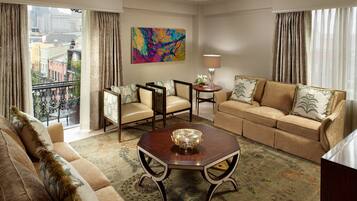 A spacious living room with a sofa, armchairs, a coffee table, and a view of the city through large windows.