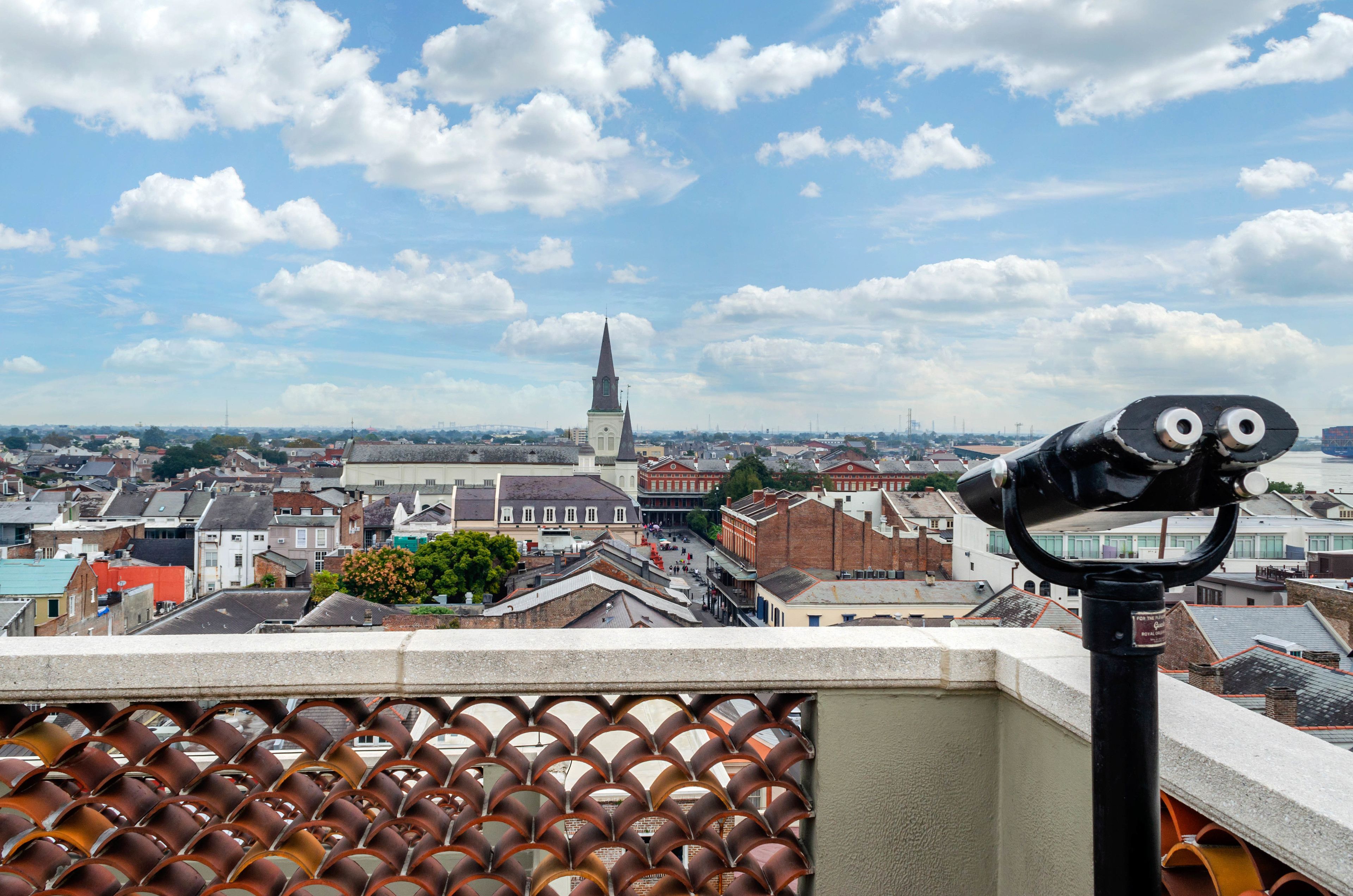 A telescope on a rooftop overlooking a cityscape with historic buildings and a prominent church spire.