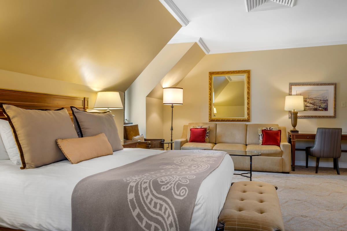 Habitació d'hotel amb un llit gran, un sofà, una taula de treball i una cadira.
