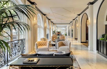 A grand hotel lobby with marble floors, ornate chandeliers, and a staircase with black railings. at Omni Royal Orleans Hotel