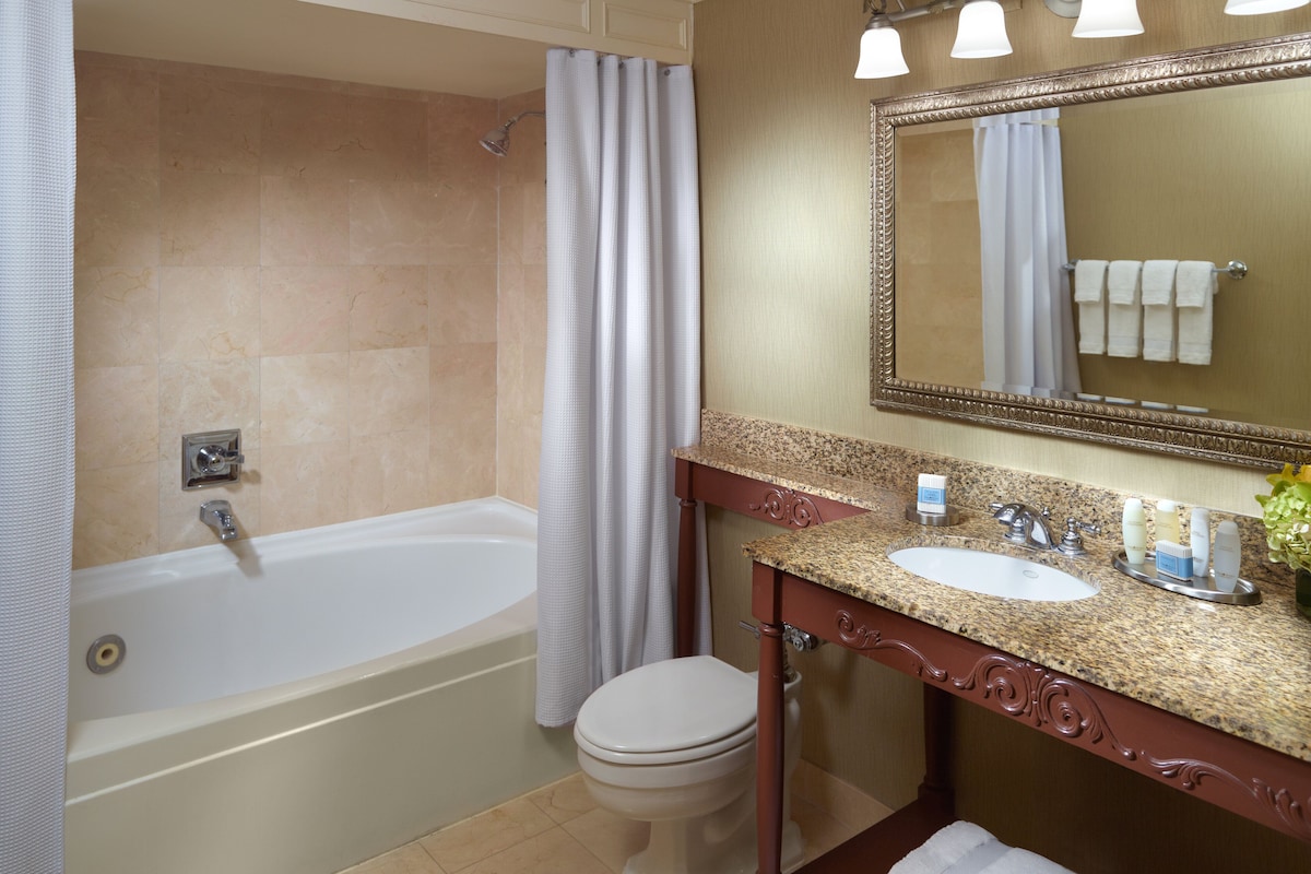 Une salle de bain équipée d’une baignoire, de toilettes, d’un lavabo et d’un miroir avec éclairage.