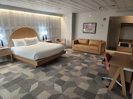 Une chambre d’hôtel avec un grand lit, un canapé, un bureau et une moquette à motifs.