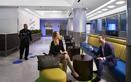 A modern hotel lobby with a reception desk, seating areas, and a reception counter.