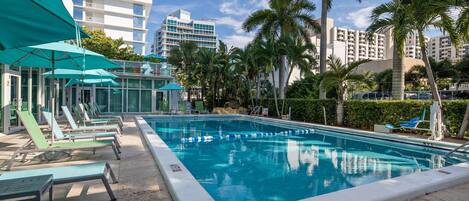 Una piscina al aire libre, sillones reclinables de piscina