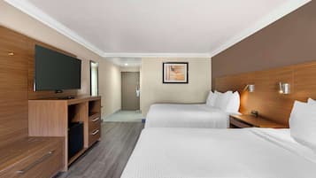 Ein Hotelzimmer mit zwei Betten, einem Fernseher, Holzmöbeln und einem Gemälde an der Wand.