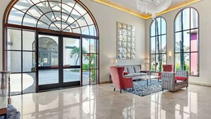 Un vestíbulo espacioso con un gran arco de vidrio, un candelabro y un área de descanso con un sofá y sillones.