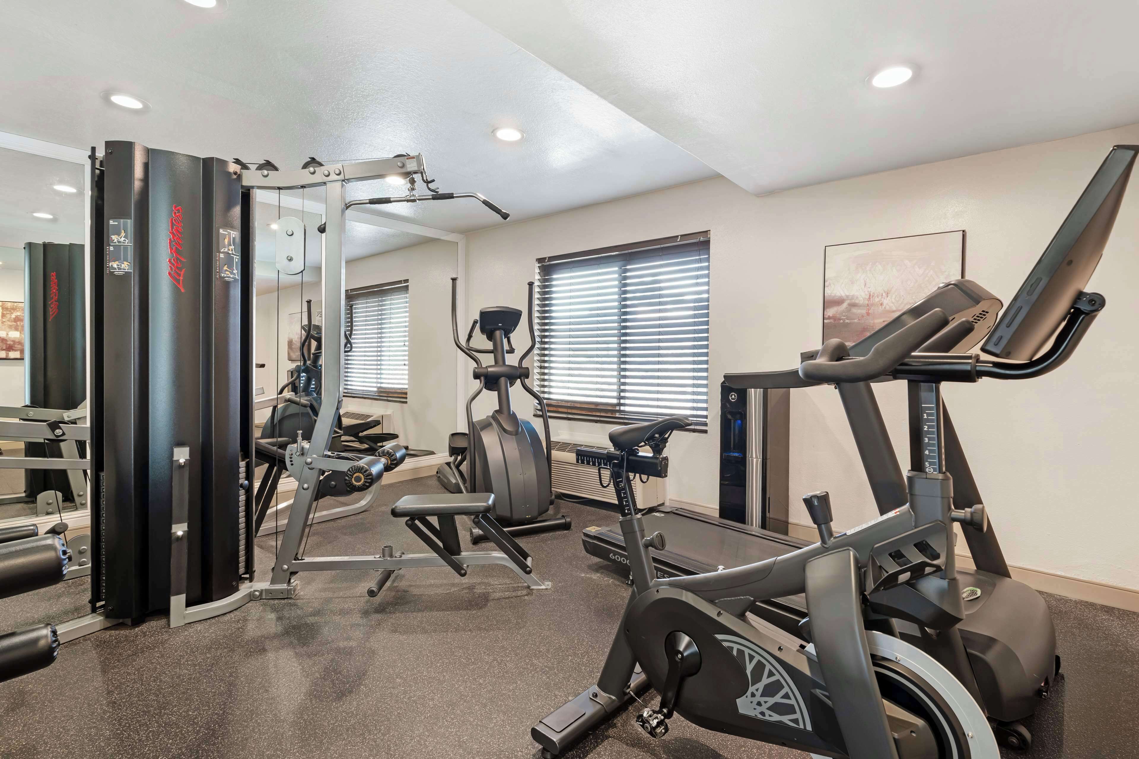 A gym with various exercise equipment, including a treadmill, elliptical, and weight machines.