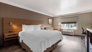 A hotel room with a large bed, bedside tables, a desk, and a window with a view.