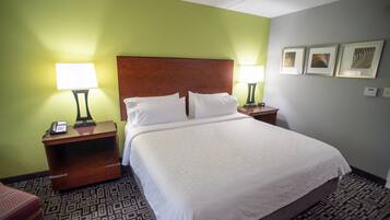 A hotel room with a large bed, two bedside tables with lamps, a telephone, and a patterned carpet.