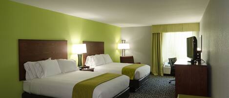 A hotel room with two beds, a desk, a chair, a television, and a window with curtains.