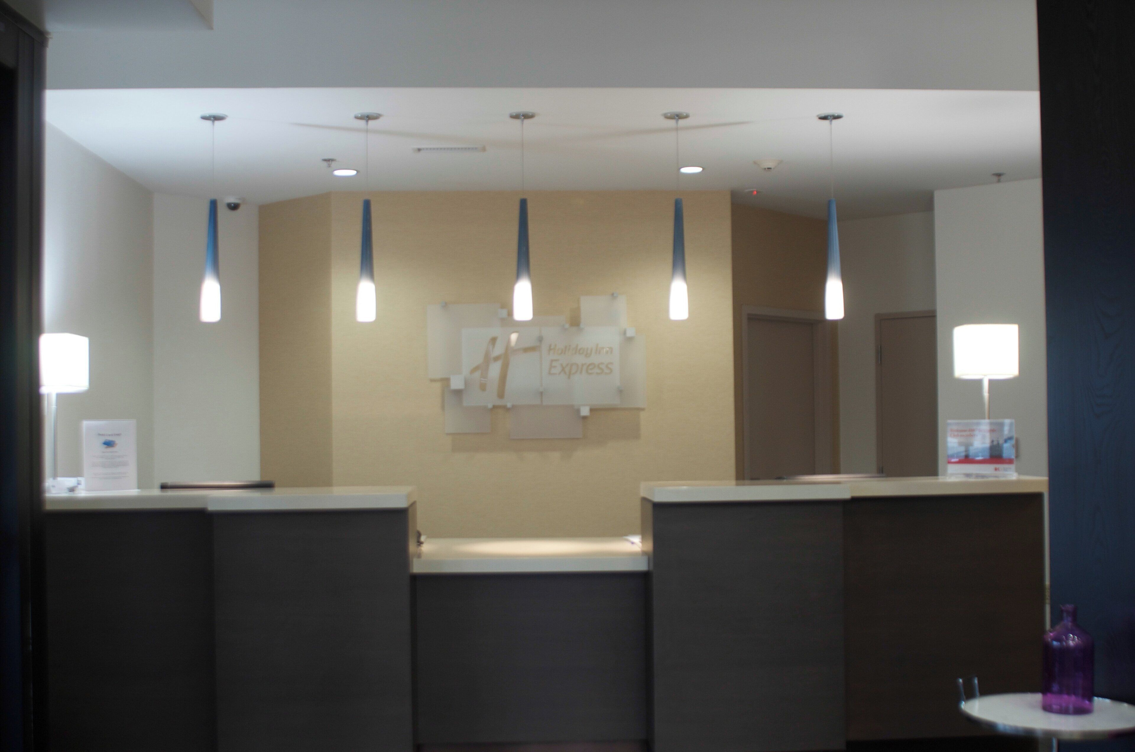 A reception area with a counter, a sign for Holiday Inn Express, and pendant lighting.