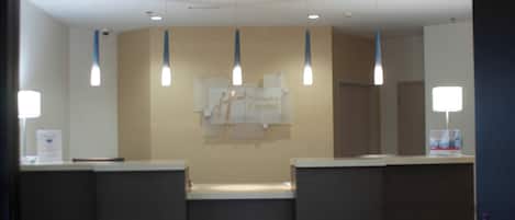 Un área de recepción con mostrador, letrero de Holiday Inn Express e iluminación colgante.