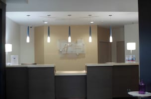 Un área de recepción con mostrador, letrero de Holiday Inn Express e iluminación colgante.