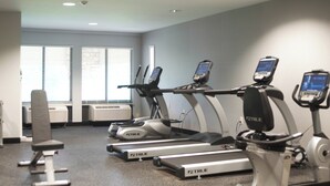 A gym with treadmills, a stationary bike, and a bench.