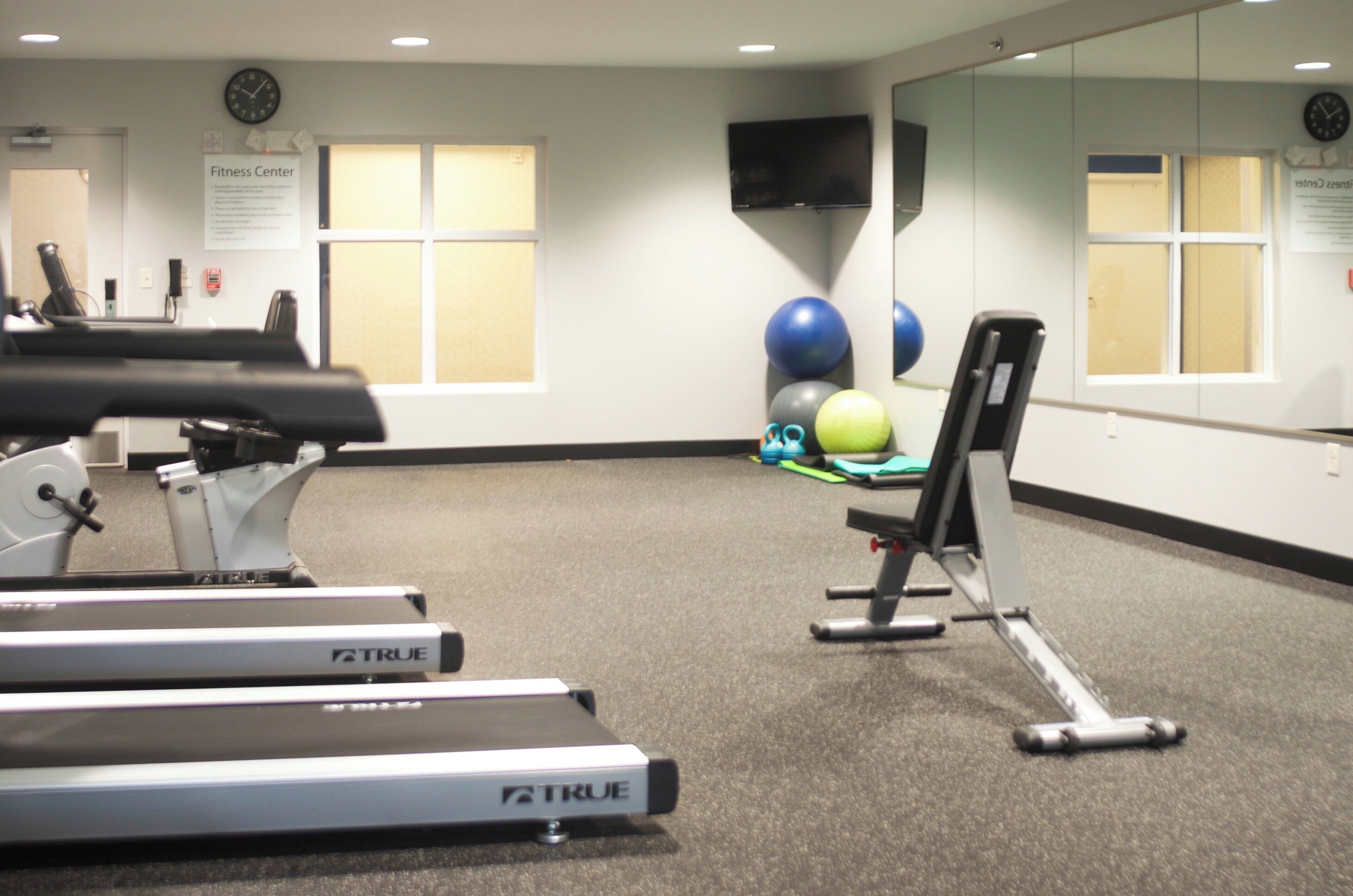 A fitness center with treadmills, exercise balls, and a mirrored wall.