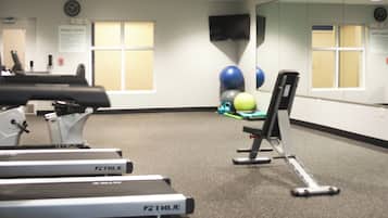 A fitness center with treadmills, exercise balls, and a mirrored wall.