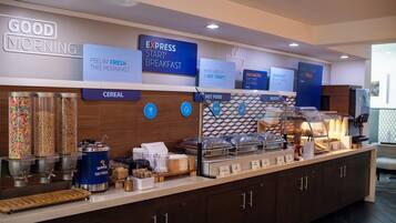 A breakfast bar with cereal, hot food, and bakery options.