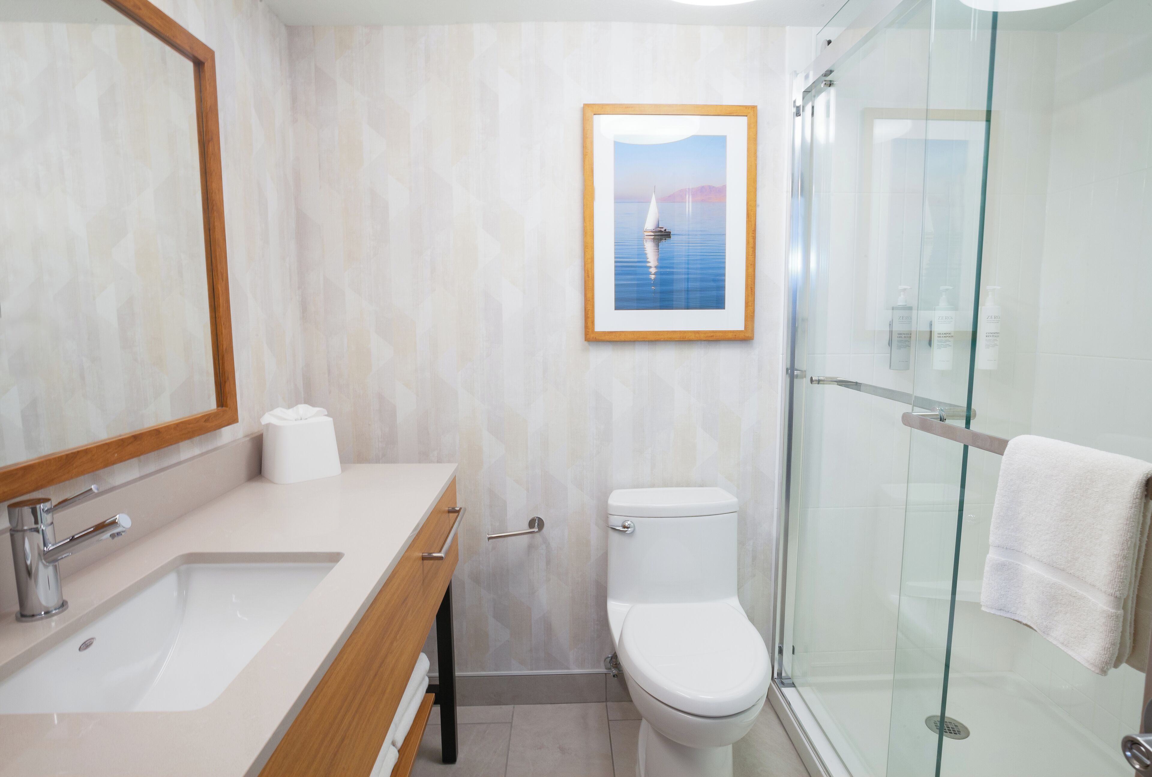 A bathroom with a sink, toilet, and glass shower enclosure.