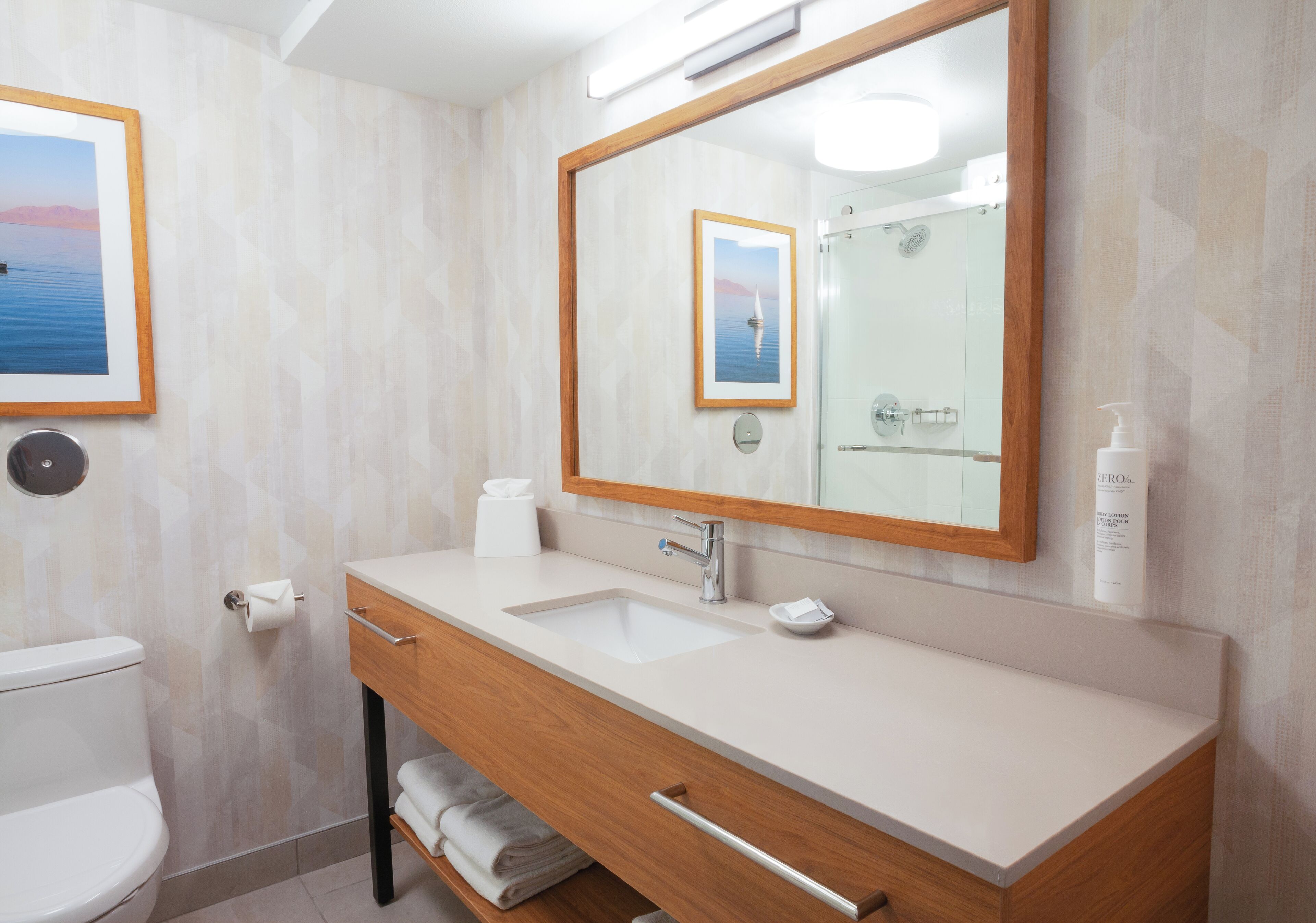 A modern bathroom with a large mirror, a sink, a toilet, and a towel rack.