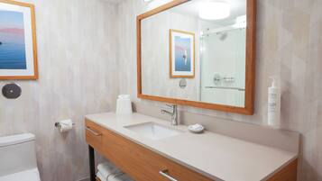 A modern bathroom with a large mirror, a sink, a toilet, and a towel rack.
