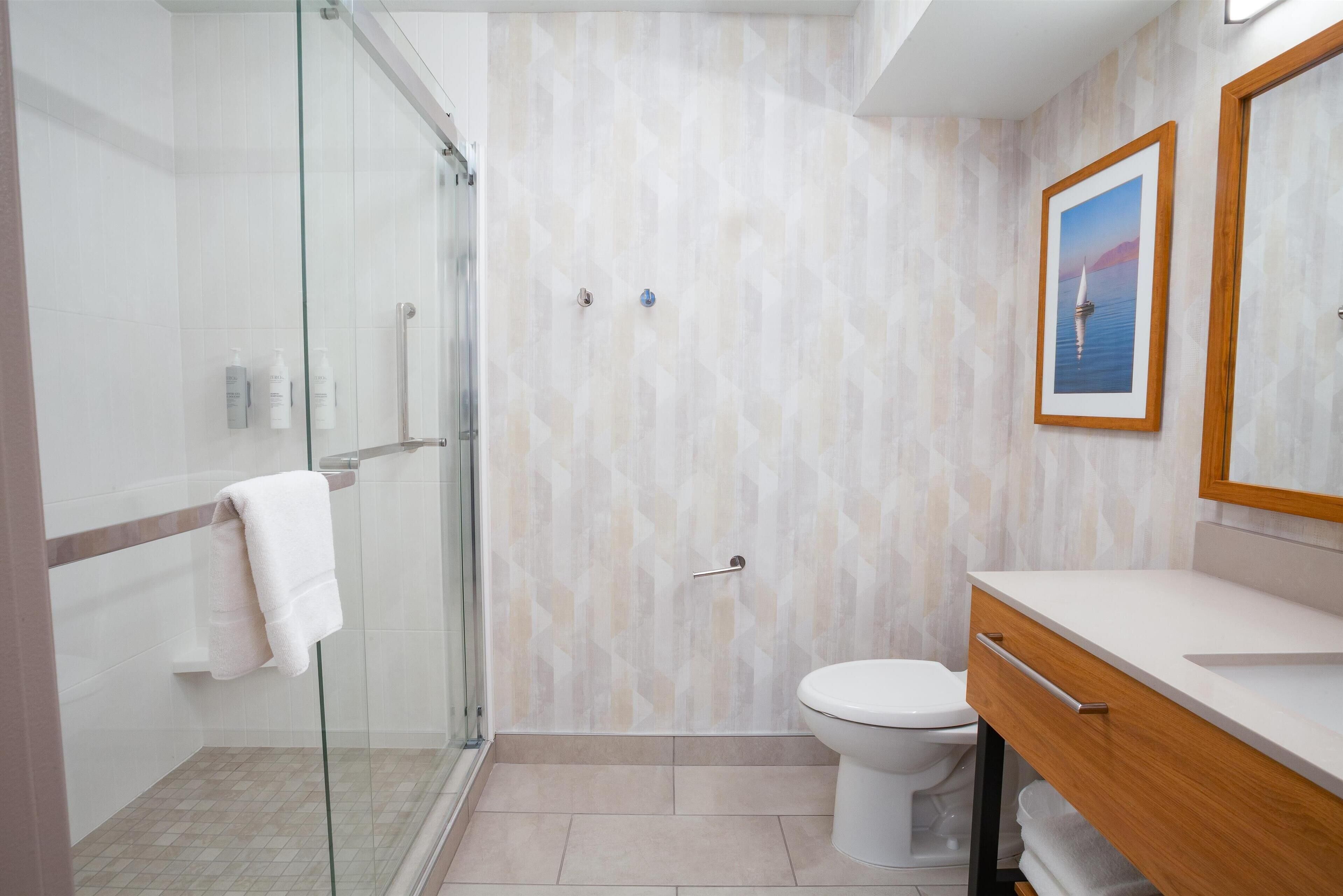 Un baño moderno con cabina de ducha de vidrio, inodoro y tocador con espejo.