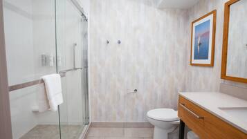 Un baño moderno con cabina de ducha de vidrio, inodoro y tocador con espejo.