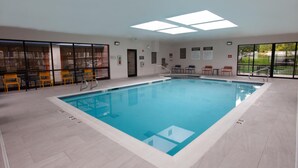 An indoor swimming pool with clear markings, adjacent seating, and a view of the outdoors.