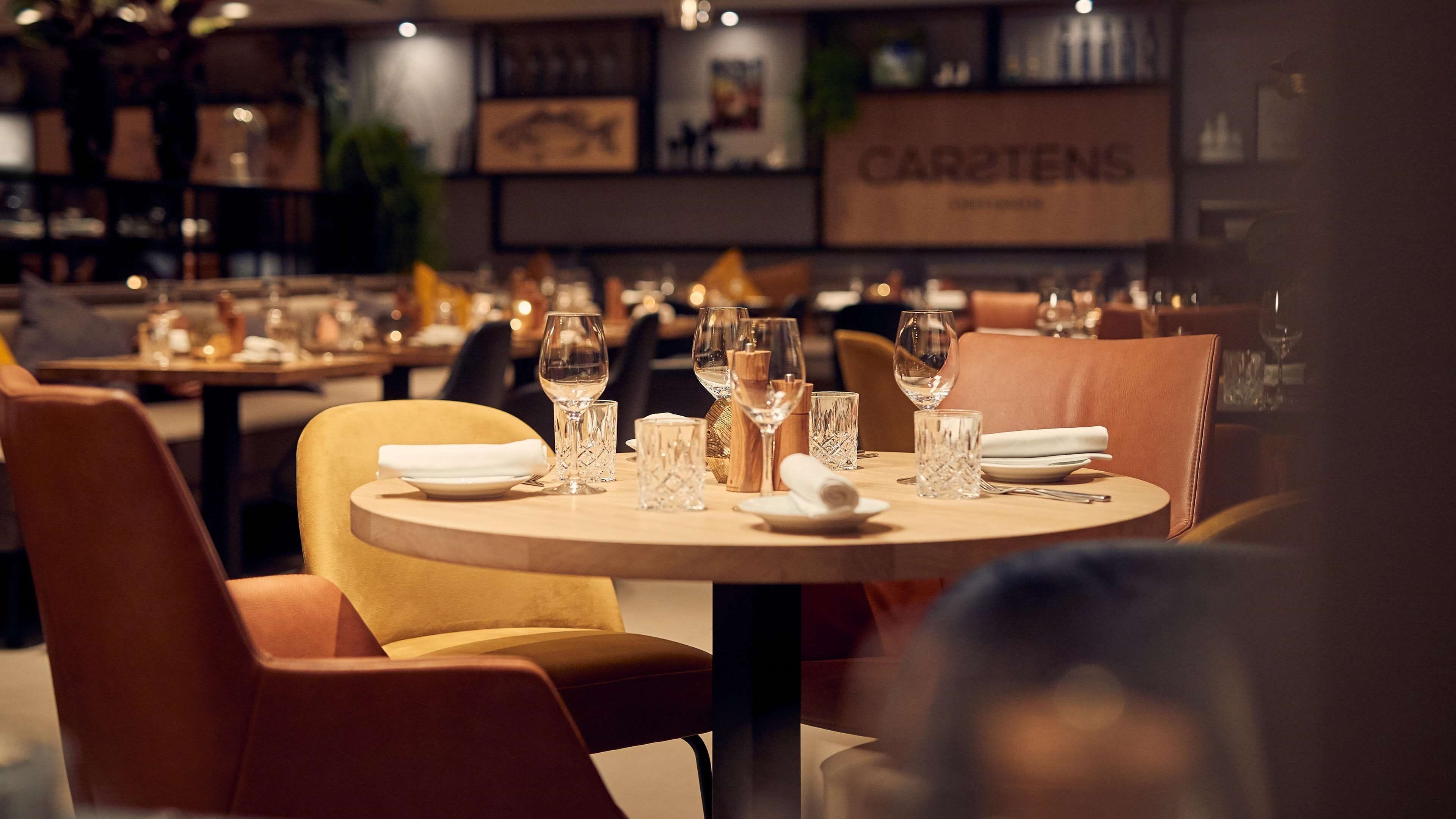 A restaurant interior with round tables, chairs, and neatly set dining tables.