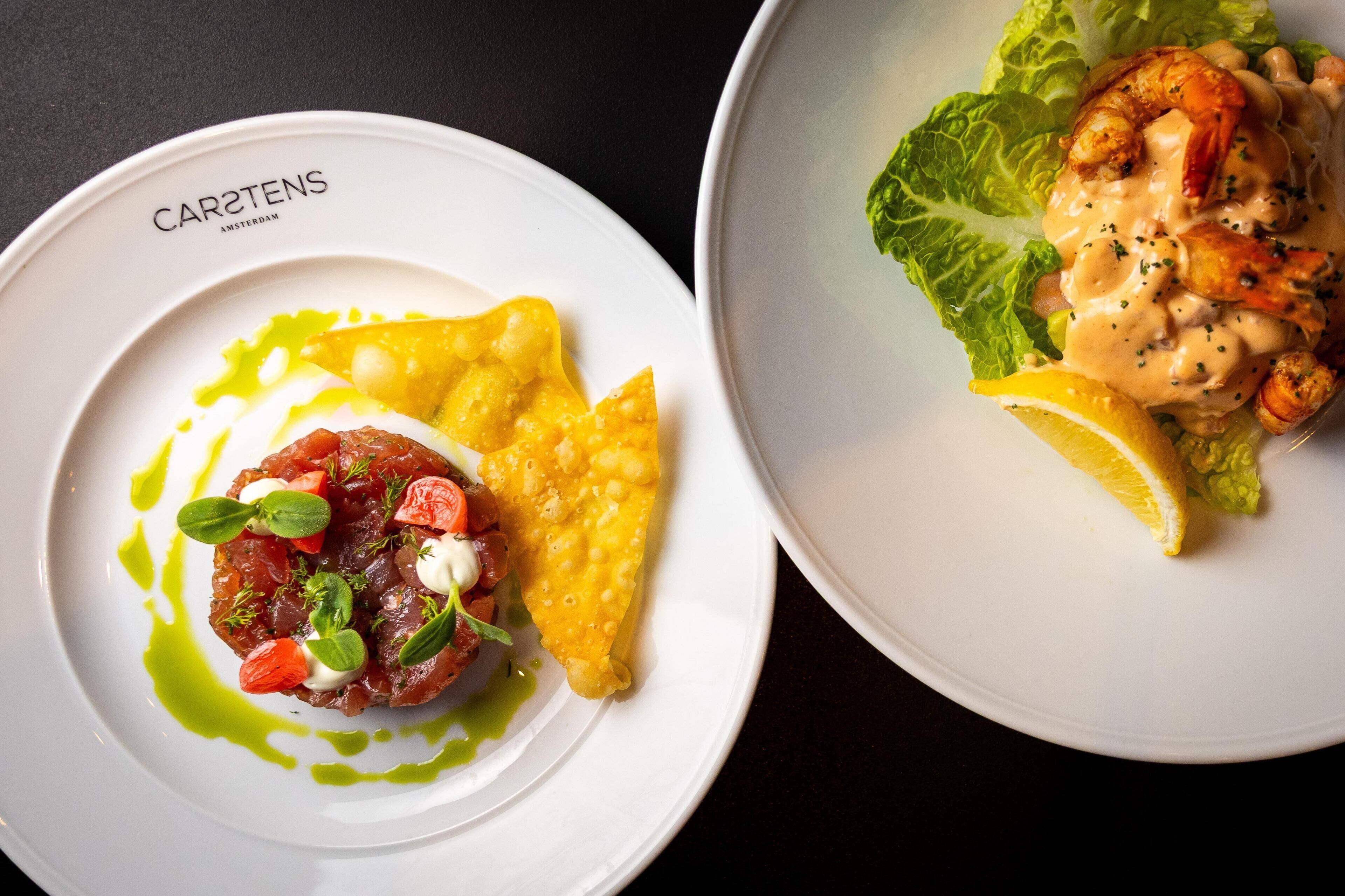 Deux assiettes de nourriture, dont l’une porte une étiquette indiquant « CARSTENS AMSTERDAM ».