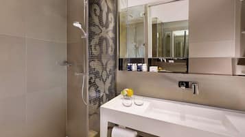 A modern bathroom with a glass-enclosed shower, a white vanity, and a large mirror.