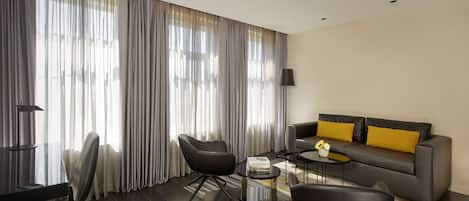 Una sala de estar moderna con un sofá, dos sillones, una mesa de centro y un televisor.