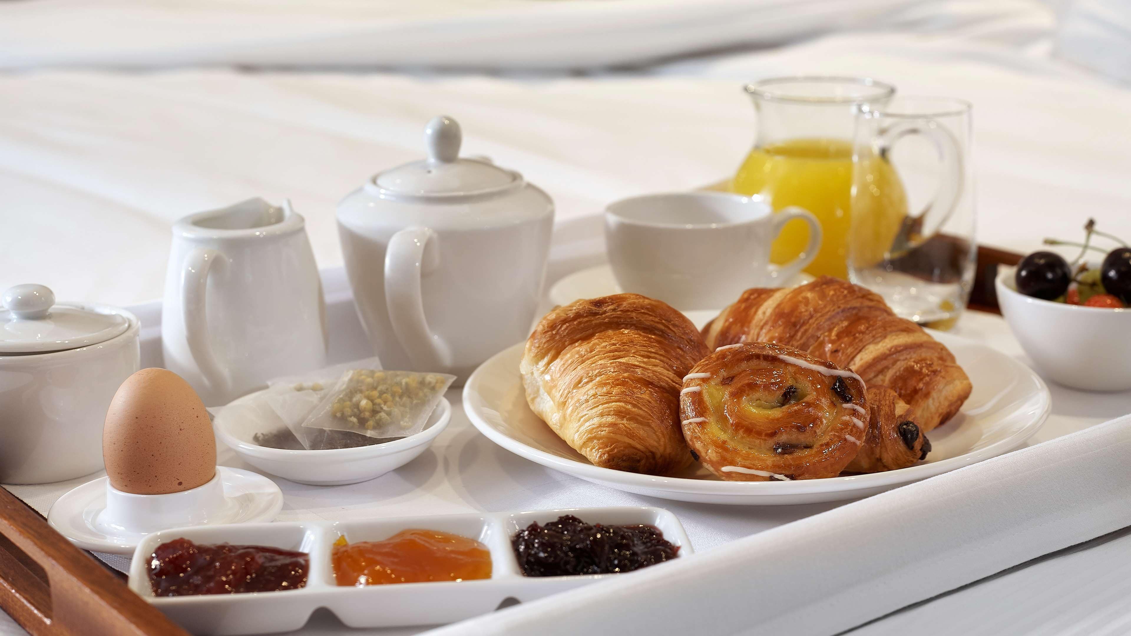 A breakfast tray with croissants, tea, and jam.