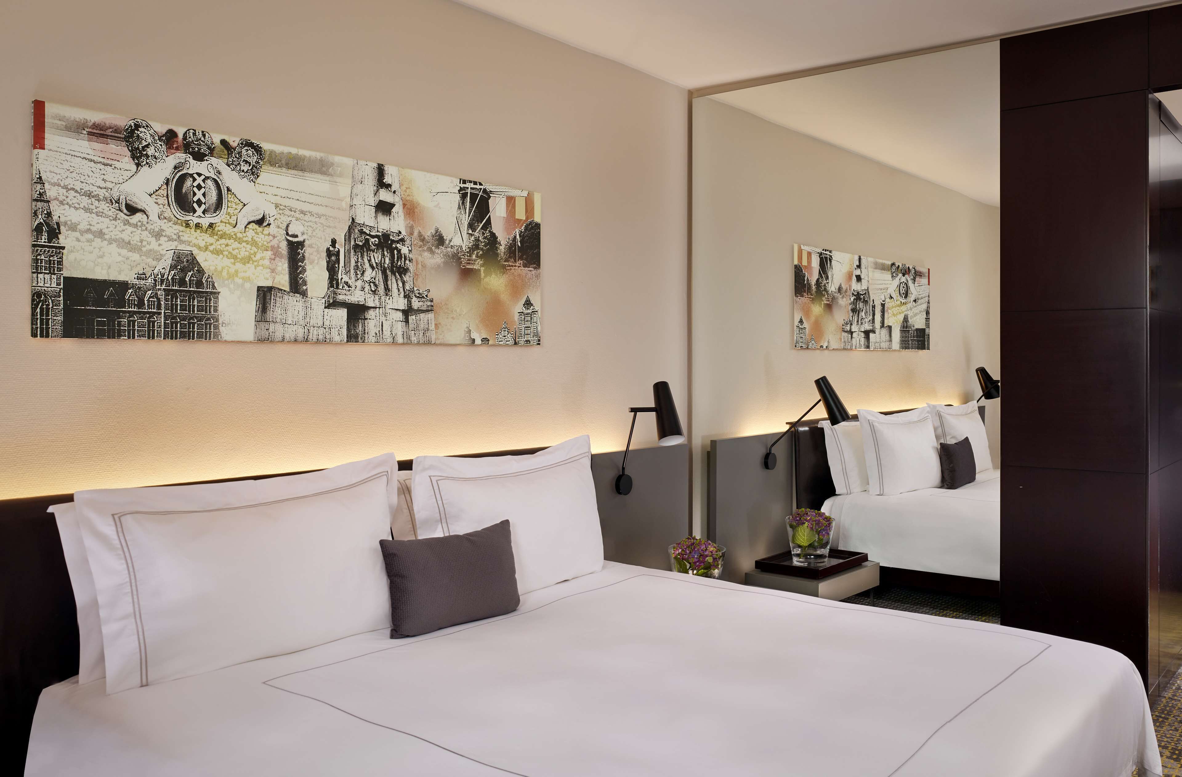 Una camera d'albergo con un letto grande, un comodino, uno specchio e un'opera d'arte appesa al muro.