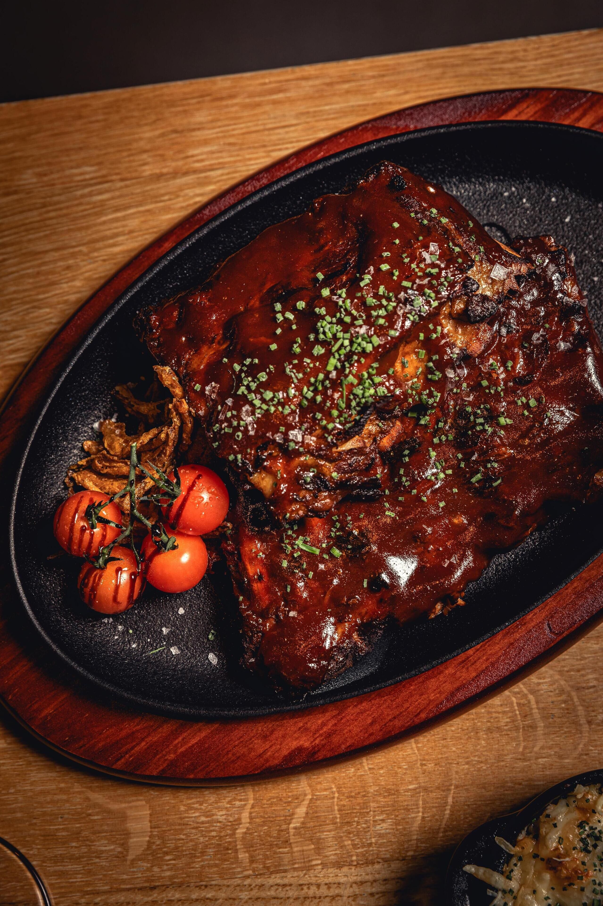 Un plato de carne glaseada con verduras y hierbas.