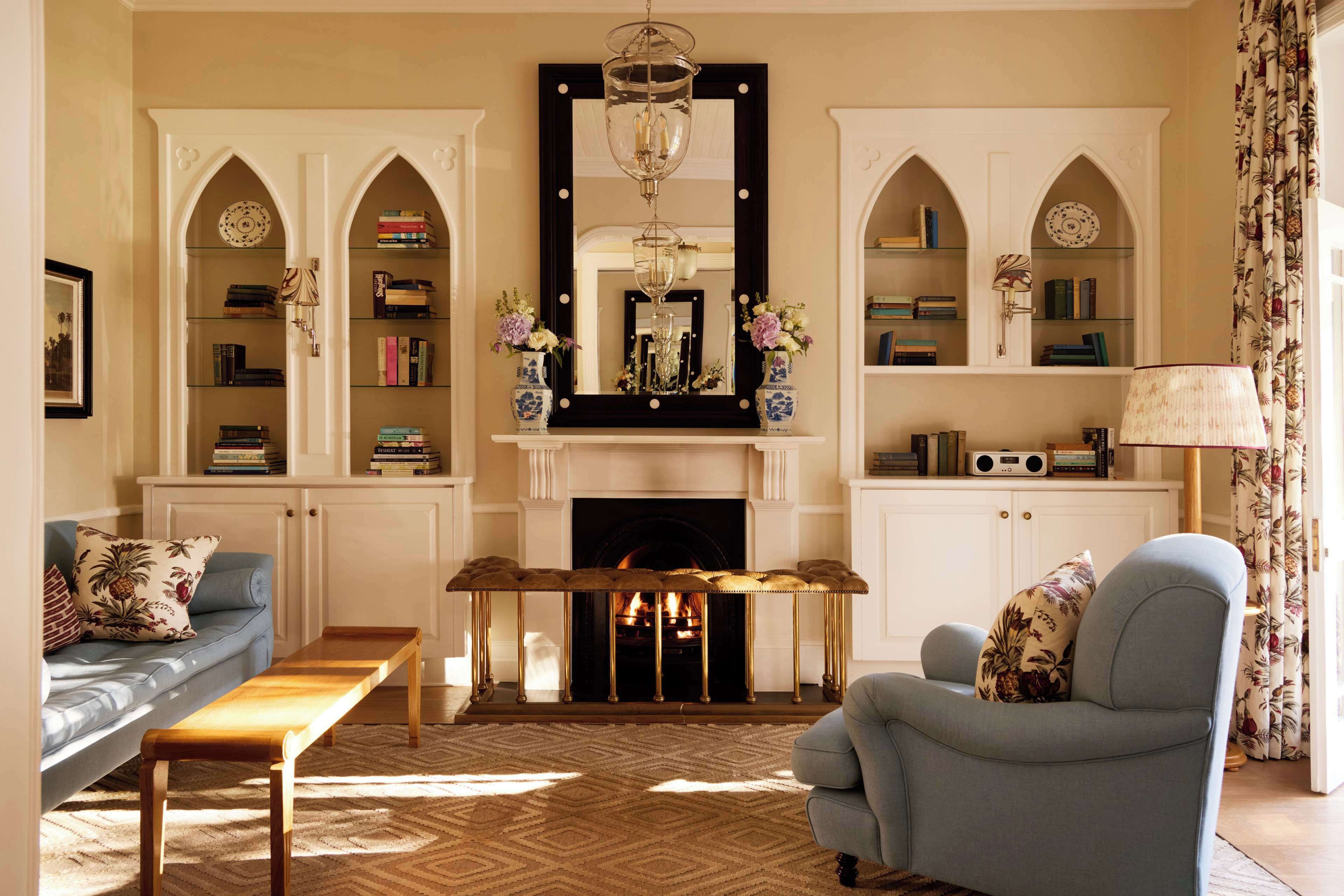 A living room with a fireplace, bookshelves, a sofa, a chair, and a table.