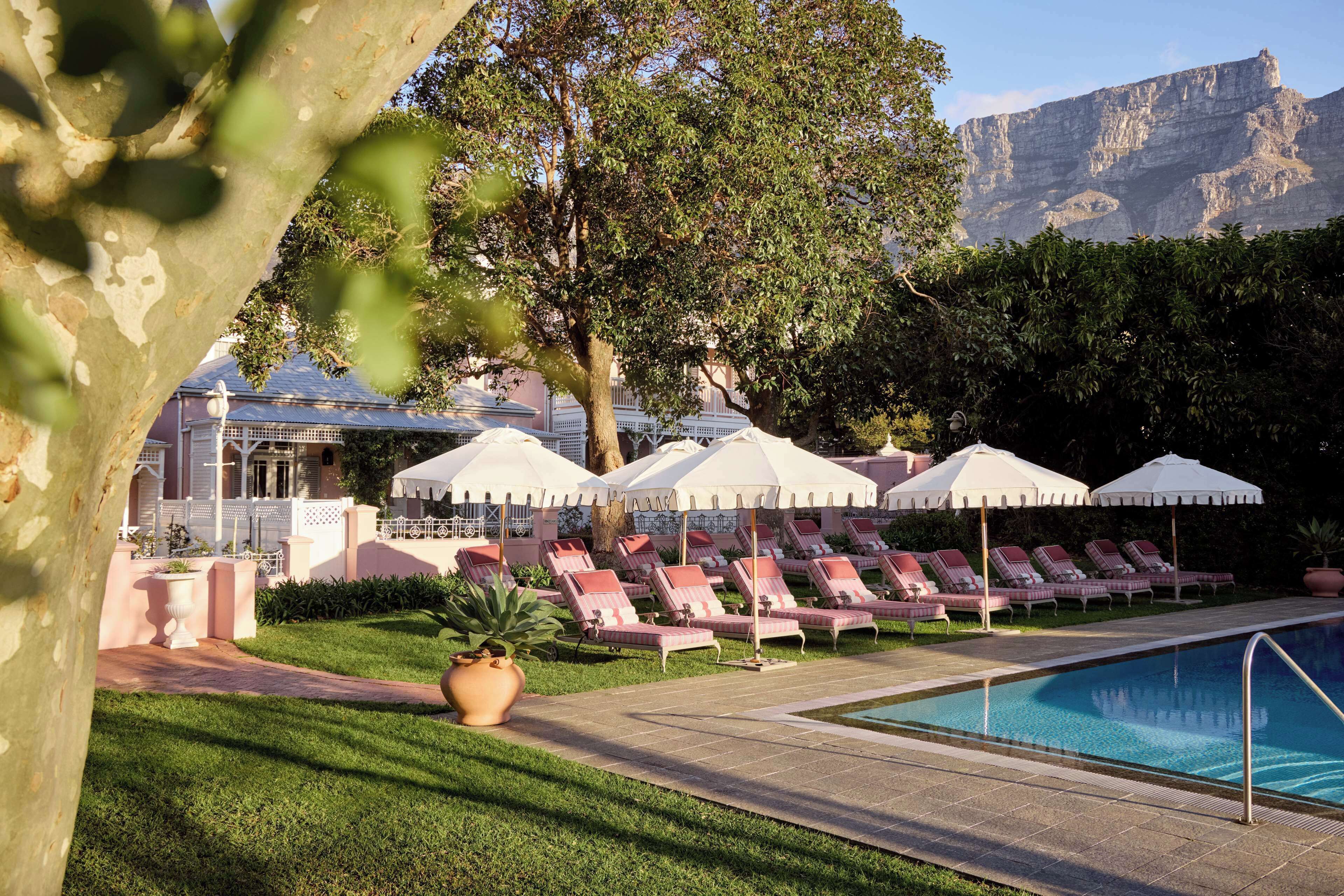A poolside area with lounge chairs and umbrellas, a pathway, and a building in the background.