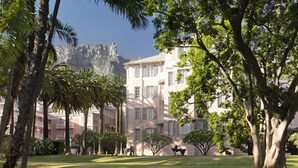 A hotel with a lush garden, palm trees, and a view of a cliff. - Mount Nelson, A Belmond Hotel, Cape Town (Cape Town)