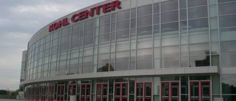 A modern building with a glass facade and red doors, labeled "Kohl Center".
